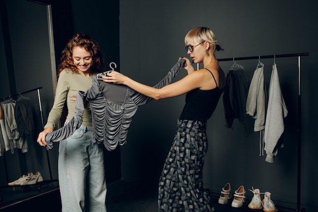 Foto stylist-ontwerper die helpt bij het kiezen van kleding voor de klant