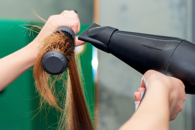 Stylist's hands drying long brown hair.