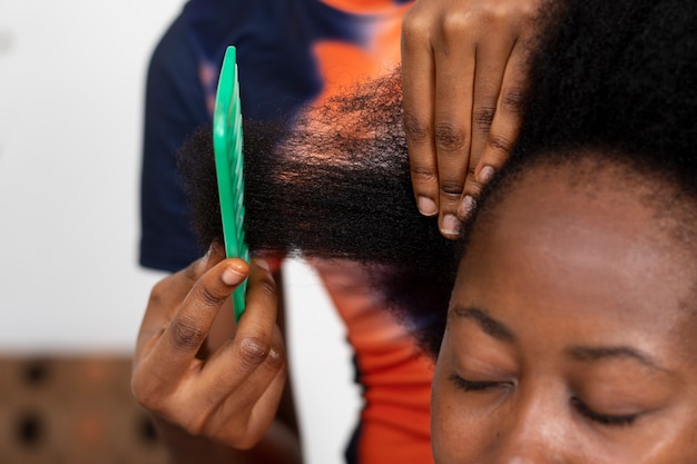 Foto stylistvrouw die voor haar cliëntafrohaar zorgt