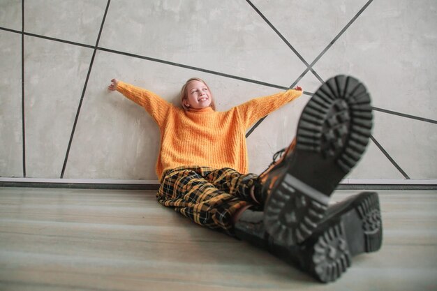 Stylized photo of a dreaming girl sitting near a wall