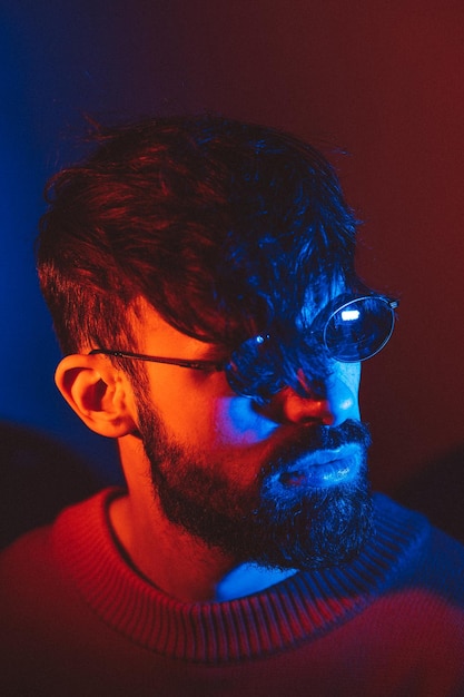 Stylized portrait of a man with a beard and black modern glasses using 2 sources of colored light