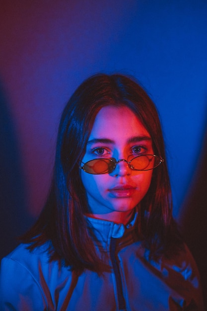 Стилизованный портрет молодой девушки в современных очках с использованием 2-х источников цветного света