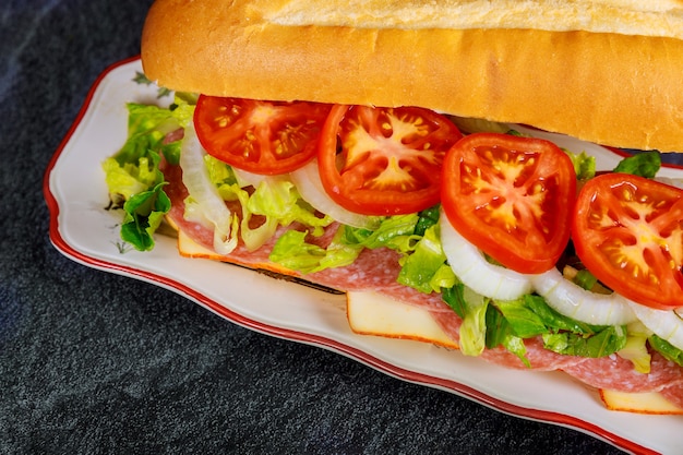 Sub made from french bread, muenster cheese, salami and vegetable. Take out food or fast food concept.