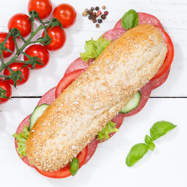 Sub sandwich whole grain grains baguette with salami square from above on wooden board