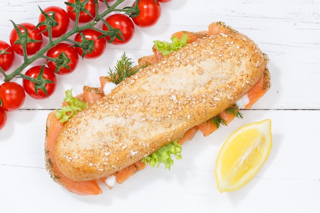 Sub sandwich whole grain grains baguette with salmon fish from above on wooden board