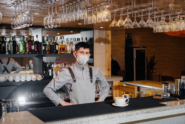 Submission of a Barista in a mask of delicious organic coffee in modern cafe during the pandemic.