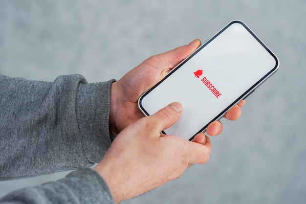 Subscribe to the Internet channel on the smartphone display. Man holds smartphone close-up with icon.
