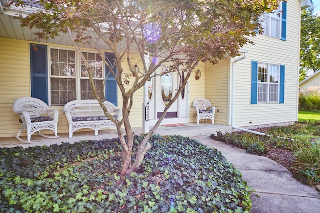 Photo suburban home with yellow siding and blue shutters welcoming porch scene