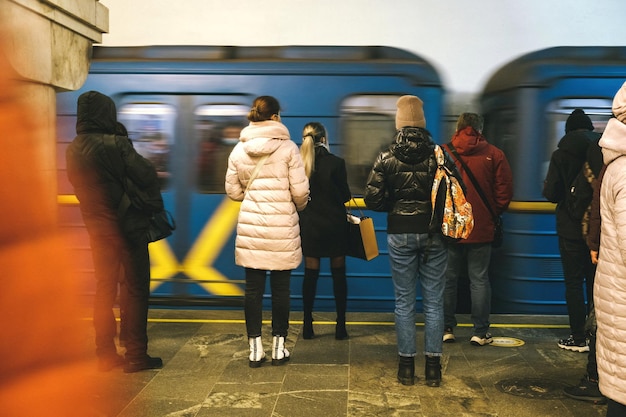 さまざまな人々の地下鉄駅が地下鉄駅に立ち、電車がwebcityに乗るのを待っています