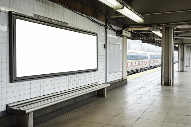 a subway station with a blank billboard on the wall