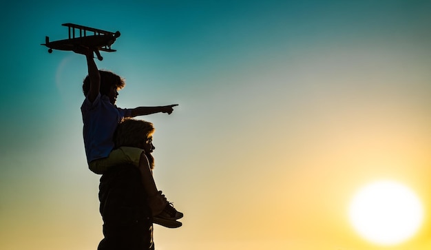 Succes en kind leider concept zonsondergang silhouet van vader en zoon samen jongenskind zit op papa schouder meeliften terwijl de vlucht