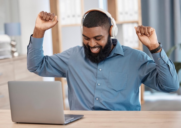 Succes van de zakenman en laptop-koptelefoon of luisteren naar nieuws of aankondiging van bonuswinst of verkoop Professionele Afrikaanse werknemer danst op muziek of opgewonden om te winnen en doelen op de computer