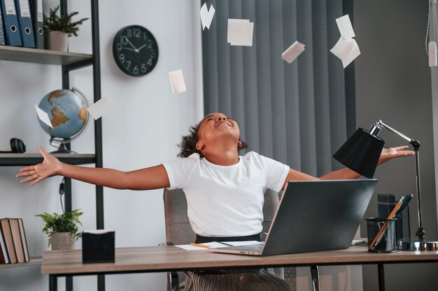 Foto succes vieren leuk vrouwelijk afrikaans amerikaans studentenkind zit bij de laptop