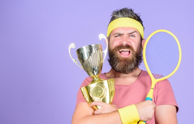 Foto successo e risultati vinci una partita di tennis vinci ogni partita di tennis a cui partecipo giocatore di tennis vince il campionato l'atleta tiene la racchetta da tennis e il calice d'oro l'uomo hipster con la barba indossa l'abbigliamento sportivo