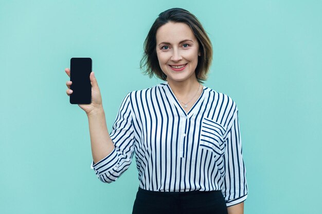 Success and beautiful business woman showing new smart phone and looking at camera with toothy smile