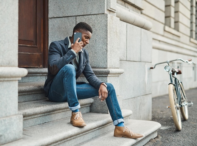 Success belongs to those who show up Shot of a young businessman using a smartphone against an urban background