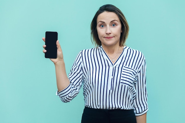 Donna d'affari di successo che mostra il nuovo smartphone e guarda la fotocamera