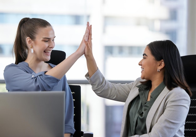 Il successo può essere anche uno sforzo di squadra inquadratura di due giovani imprenditrici che si danno il cinque in un ufficio al lavoro