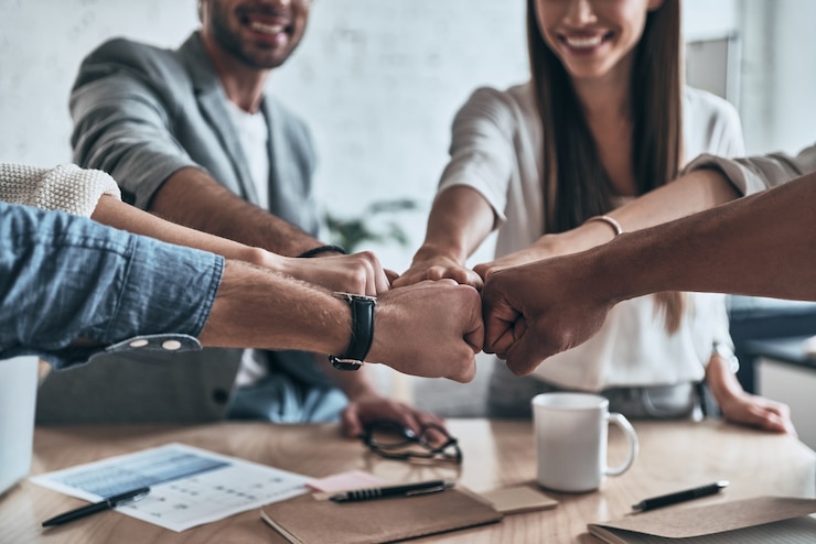 Photo success!  close up of business colleagues holding fists together in a symbol of unity and smiling while working in the board room