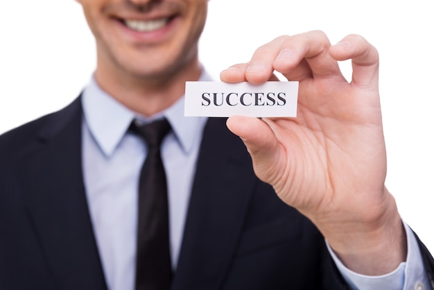 Success! Close-up of young man in shirt and tie holding paper with success printed on it