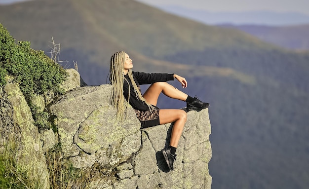 Success concept mountain traveling and hiking rock climbing mountaineering lover reaching the top woman relax on mountain cliff feel freedom extremely free alpinism lifestyle way to success