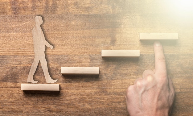 Success concept with wooden businessman climbing wooden block stairs