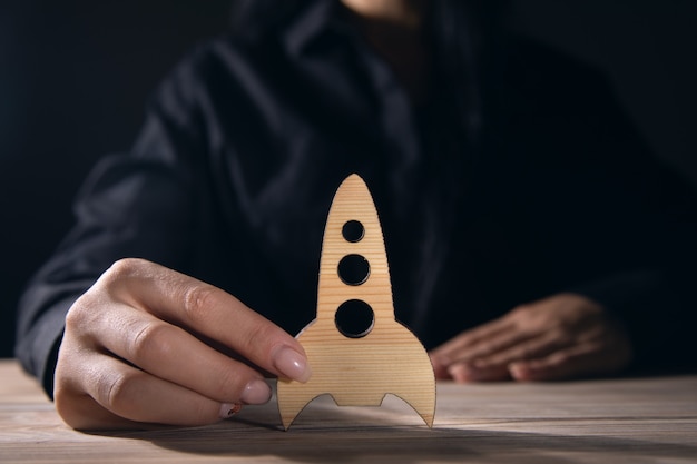 Success concept, women holding a wooden rocket