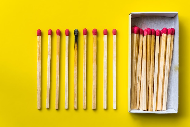 Success, defeat, achievement. the concept of happiness. matches on a yellow background. burnt dark match among normal matches. burning match fire to its neighbors, a metaphor for ideas and inspiration