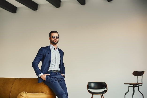 Il successo in tutto ciò che un bell'uomo d'affari elegante in abito elegante e occhiali da sole scuri è in piedi