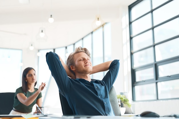 Foto il successo fa bene inquadratura di un designer soddisfatto che si appoggia allo schienale della sedia in un ufficio moderno