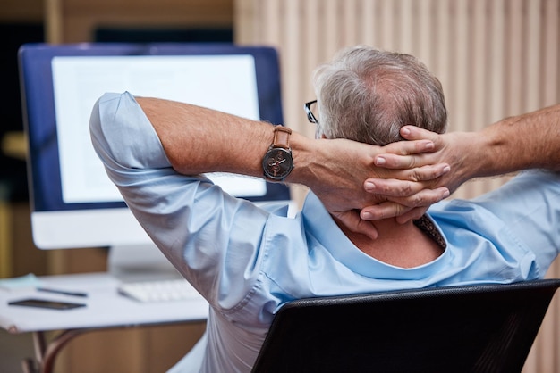 Success feels great Shot of an unrecognizable businessman sitting alone in his office and feeling accomplished while using his computer