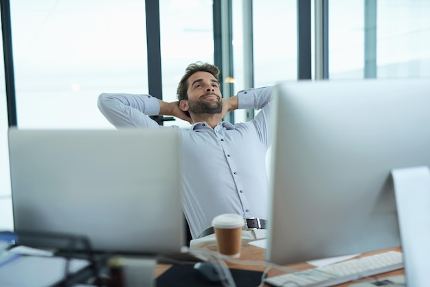 Success feels great Shot of a young corporate businessman taking a break at an office desk