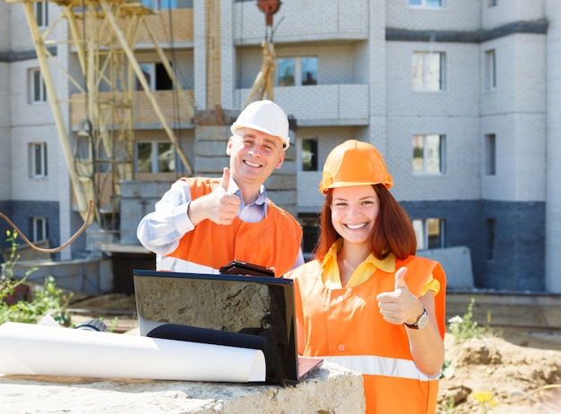 Success female and male construction workers   with a laptop and drawings
