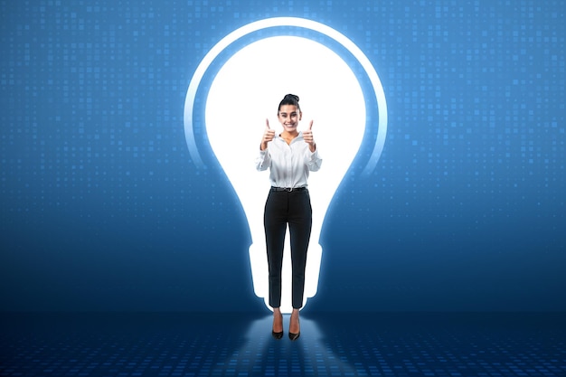 Success idea concept with happy woman with thumbs up on illuminated hole in form of light bulb on blue wall background