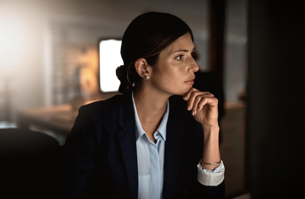 Success is defined by hard work and dedication Shot of a young businesswoman working online during a late night in a modern office