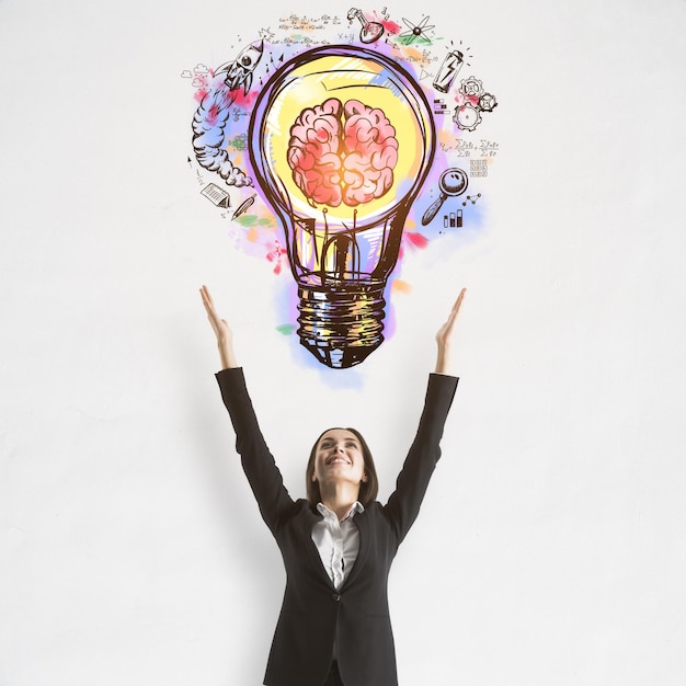 Success and startup concept with handwritten colorful sketch of light bulb and human brain above joyful businesswoman on concrete wall background