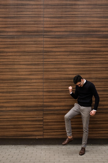 success triumph yes gesture. joy of professional achievement. happy business man celebrating. wood texture wall background. outdoors street. copyspace concept