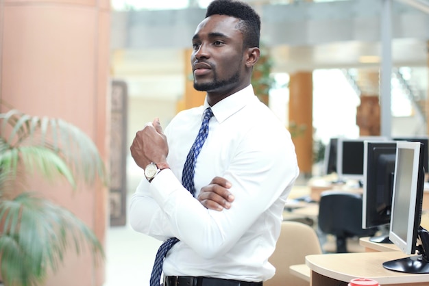 Successful African American businessman businessman standing in office.