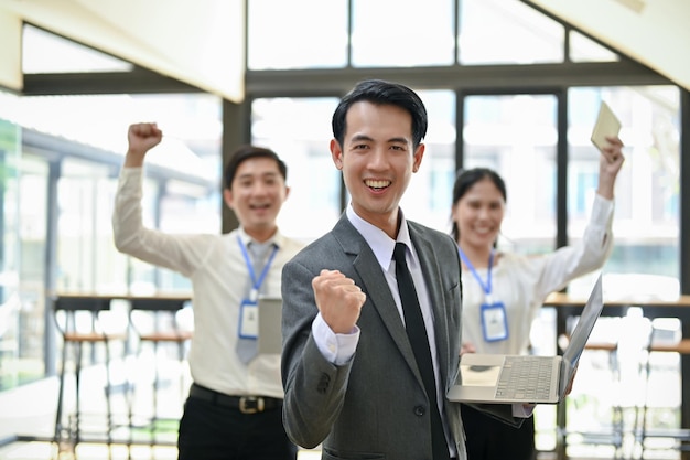 A successful Asian male CEO smiling and showing a clenched fist rejoicing and celebrating