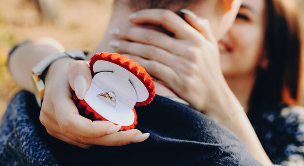 Photo successful asking for marriage of a caucasian man with red ring box embraced by his future wife