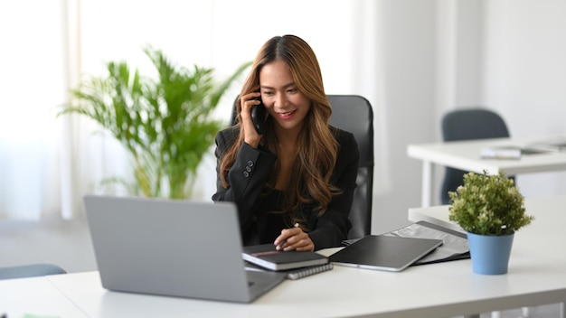 Manager femminile asiatico di successo e attraente che ha una telefonata con i suoi partner commerciali