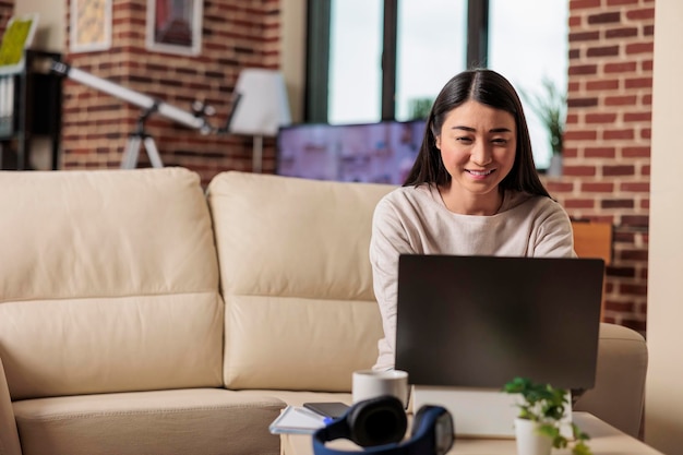 홈 오피스에서 일하는 동안 노트북 컴퓨터에서 튜토리얼 비디오 창의적인 아이디어를 보는 성공적인 정통 아시아 여성 프리랜서. 긍정적인 행복 온라인 웹 3.0 사용자 기술 응용 프로그램 개발