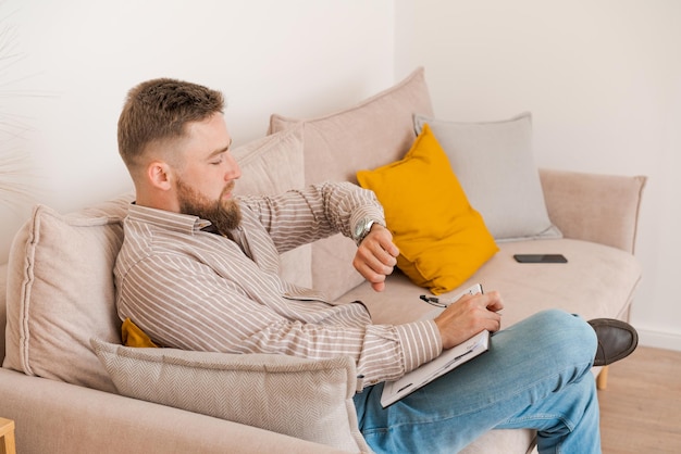 Successful bearded young man writes notes in notebook while sitting at home