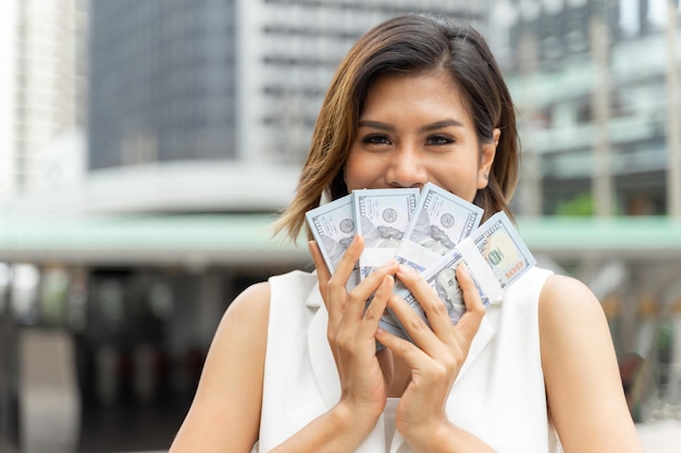 Successful beautiful Asian business woman holding money US dollar bills in hand business concept