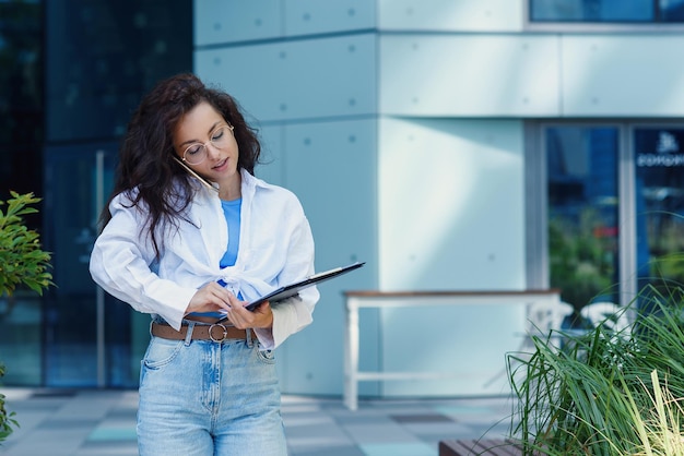 Successful beautiful business woman in suit with document walking to the meeting near modern office