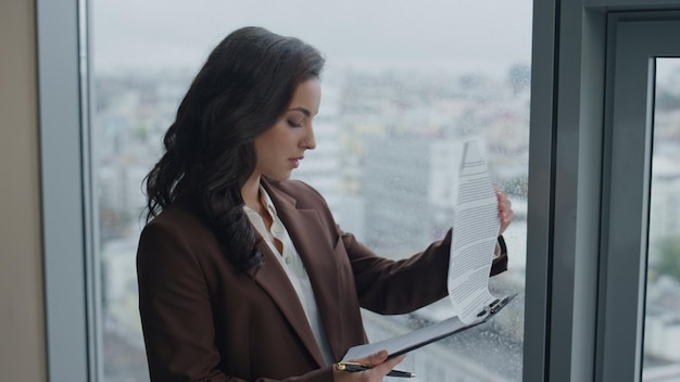 Successful boss reading contract at office window close up woman feeling happy