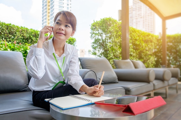 Successful business asian woman talking on her cell phone while seated outdoors in the city.