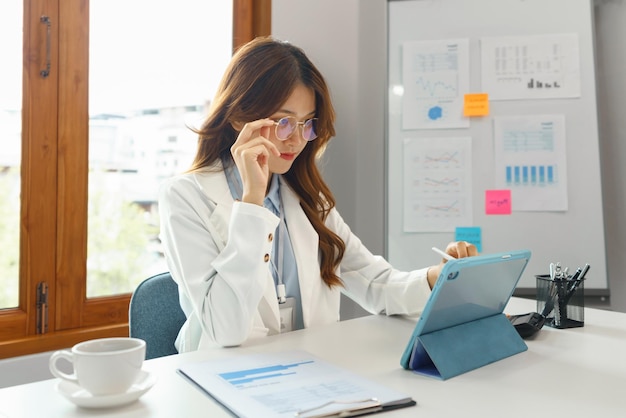 Successful business concept businesswoman use hand to holding glasses while writing data on tablet