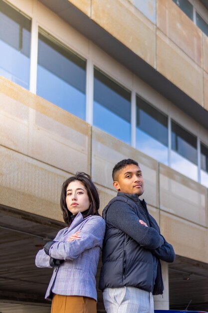 Successful business couple back to back with arms crossed on the street Concept of successful couple with crossed arms outdoors