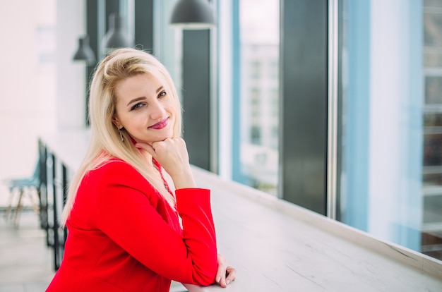 successful business lady in a red suit in a light office building by the window